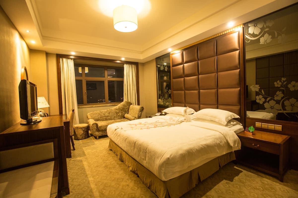 Une chambre d’hôtel avec un grand lit, un bureau, une chaise et un téléviseur.