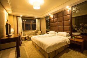 A hotel room with a large bed, a desk, a chair, and a television. - Hailian International Hotel (Ji'an)