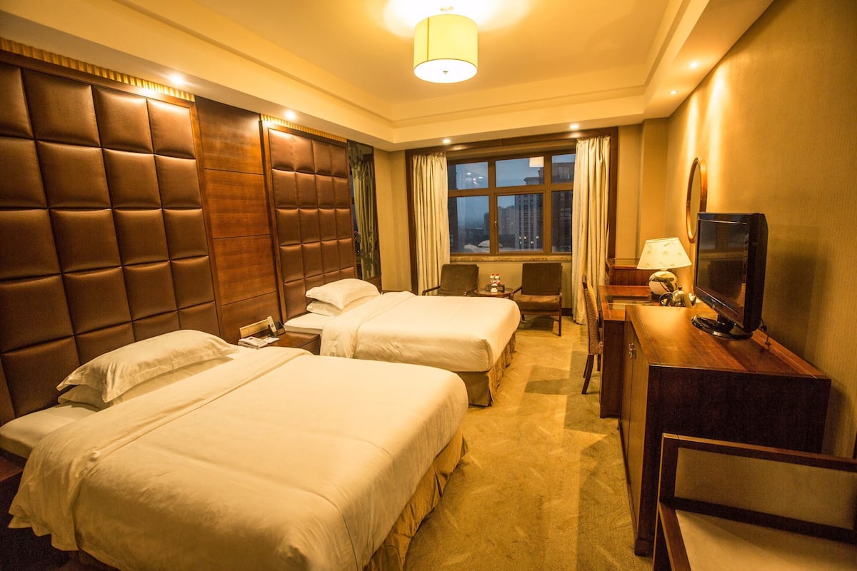Une chambre d’hôtel avec deux lits, une télévision, un bureau et une fenêtre donnant sur la ville.