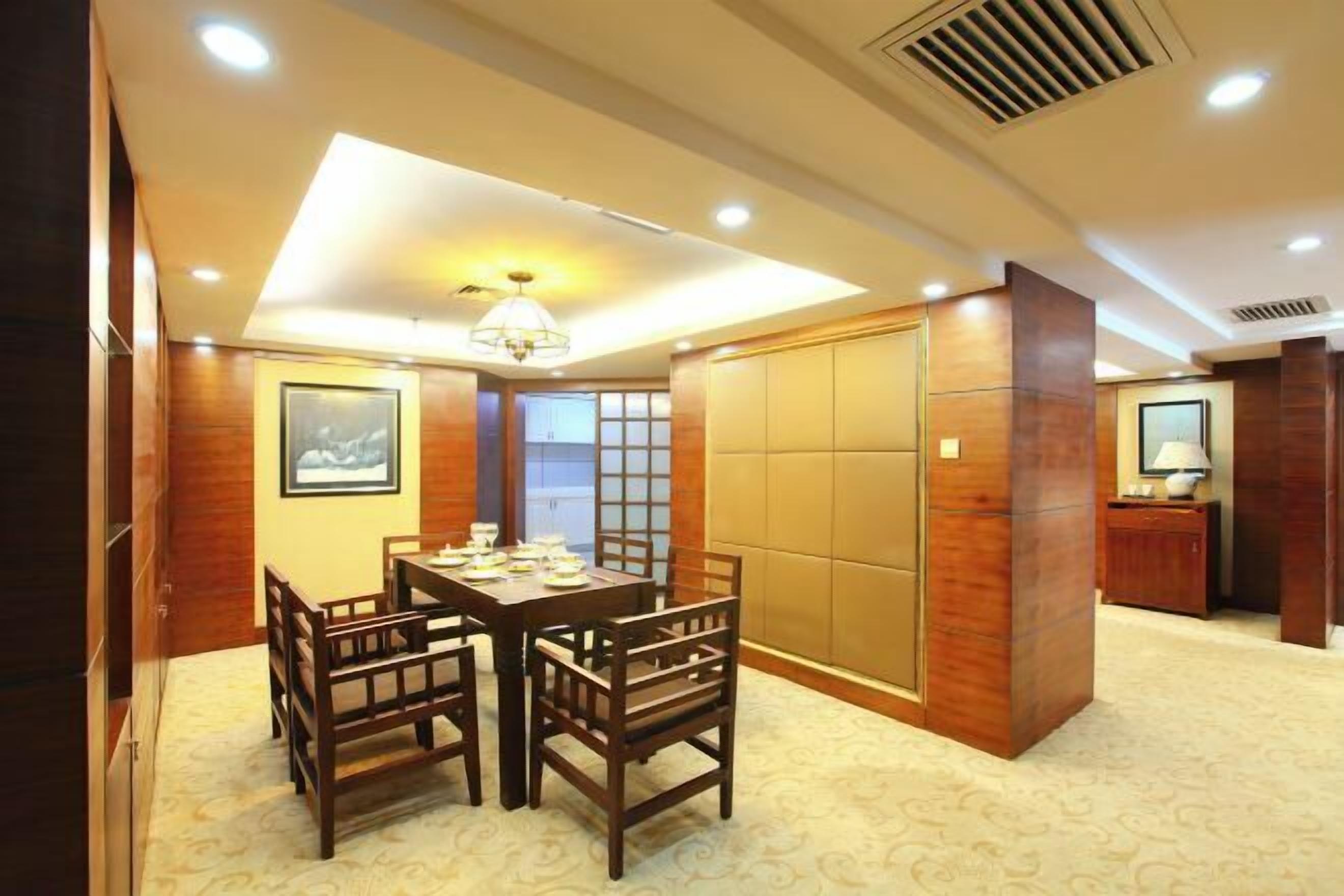 Un comedor con una mesa y sillas de madera, una araña y una puerta corredera con un panel.
