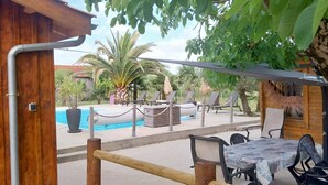 A wooden deck with a pool, lounge chairs, and a table with chairs.