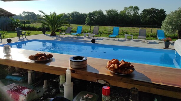 A poolside area with lounge chairs and a table with food and drinks.