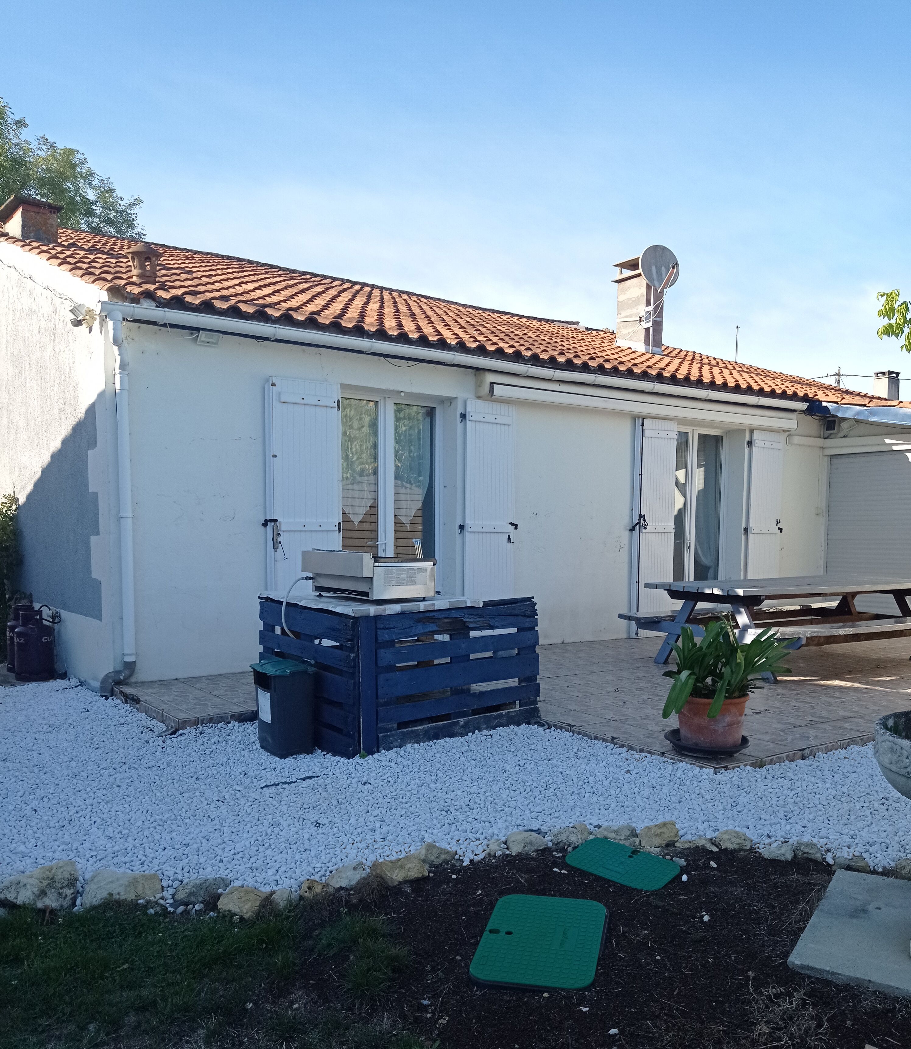 Ein Gebäude mit Ziegeldach, weißen Außenwänden und einer überdachten Terrasse.