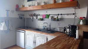 A kitchen with a wooden countertop, a coffee maker, a kettle, and a sink.