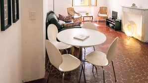 Ein Zimmer mit einem runden Tisch, zwei Stühlen, einer Couch, einem Fernseher und einem Kamin.