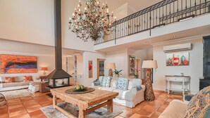 A spacious living area with a wooden coffee table, white sofas, a large chandelier, and a staircase. - Experience Ultimate Luxury and Convenience at our 5-Star Villa with Private Pool (Teulada, Moraira)