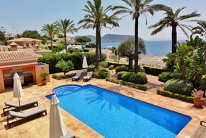 A swimming pool with lounge chairs and umbrellas, surrounded by palm trees and a view of the sea. - Experience Ultimate Luxury and Convenience at our 5-Star Villa with Private Pool (Teulada, Moraira)