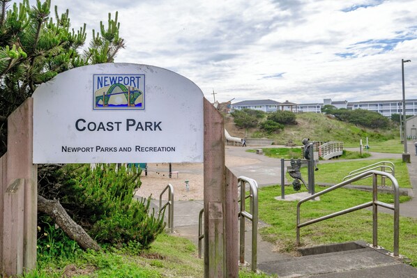 A sign for Newport Coast Park with a bridge and beach in the background.