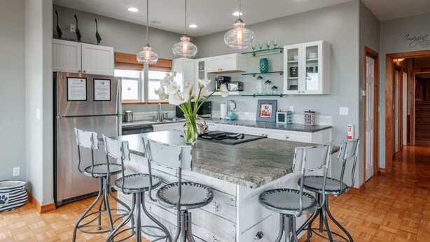 A modern kitchen with a central island, bar stools, stainless steel appliances, and decorative lighting. - Whitewater Ocean View, Spa, Secret Game Room, 800 SF Master Suite (Newport)