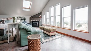A spacious loft bedroom with a large window, a fireplace, and a cozy seating area. - Whitewater Ocean View, Spa, Secret Game Room, 800 SF Master Suite (Newport)
