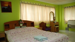 A bedroom with a bed, a desk, a chair, a mirror, and a bathroom area. - Blue Lagoon Guest House and Bar (Cha-am)