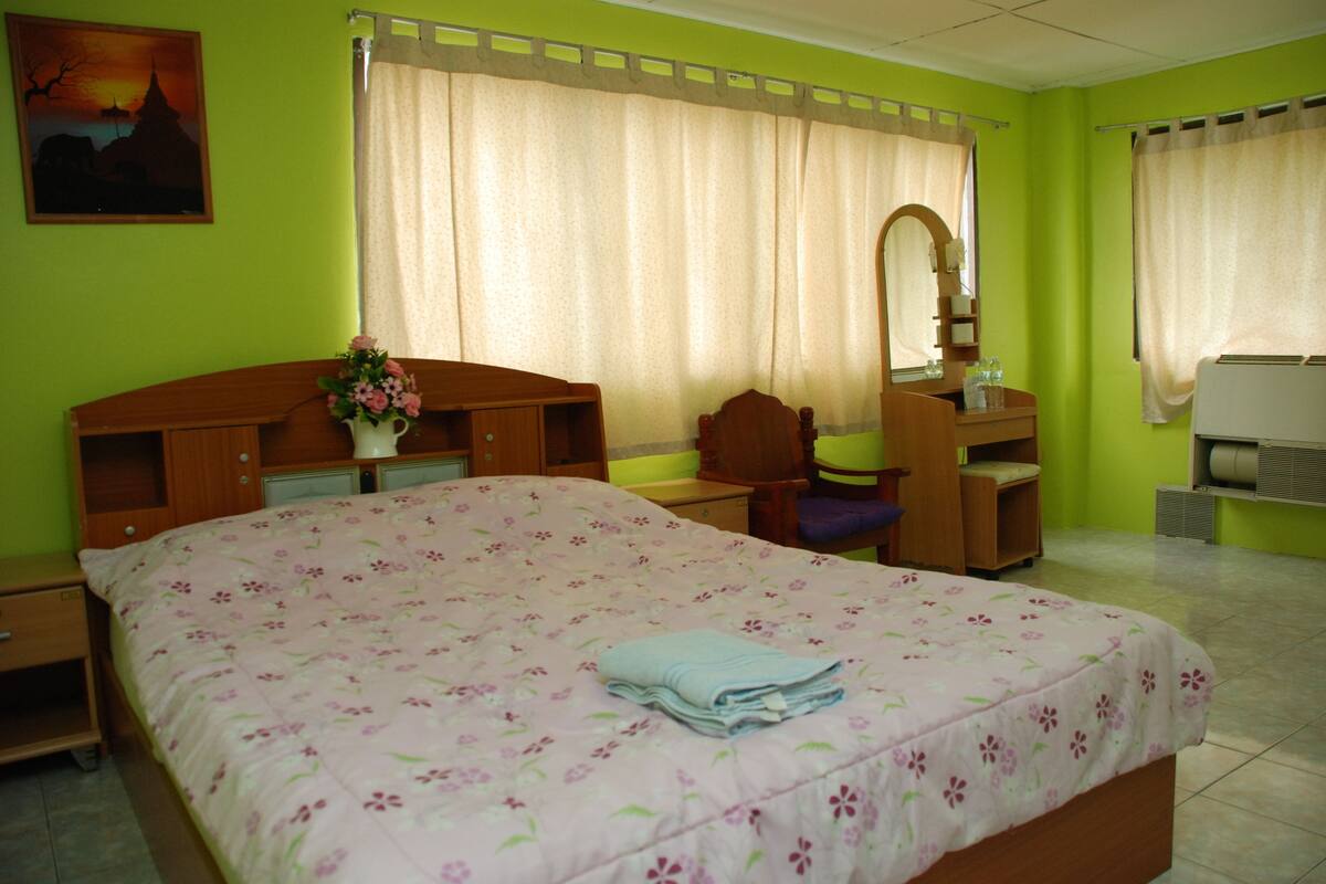 Une chambre comprenant un lit, un bureau, une chaise, un miroir et un coin salle de bain.