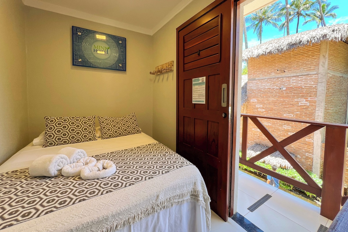 A hotel room with a bed, towels, a door to a balcony, and a wall with a framed picture.