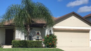 A residential house with a garage, a palm tree, and a well-maintained lawn.