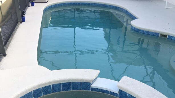 A hot tub with a blue-tiled edge, surrounded by a white deck.