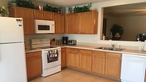 A kitchen with wooden cabinets, a white refrigerator, a microwave, a stove, and a dishwasher.