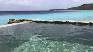 Ein klares Schwimmbecken mit Blick auf den Ozean und eine felsige Küstenlinie.