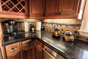 A kitchen with wooden cabinets, a coffee maker, a paper towel holder, and a tiled backsplash. - A Few Steps to the Beach! Ocean Views, Patio and 1 Car Garage Parking! (Laguna Beach)