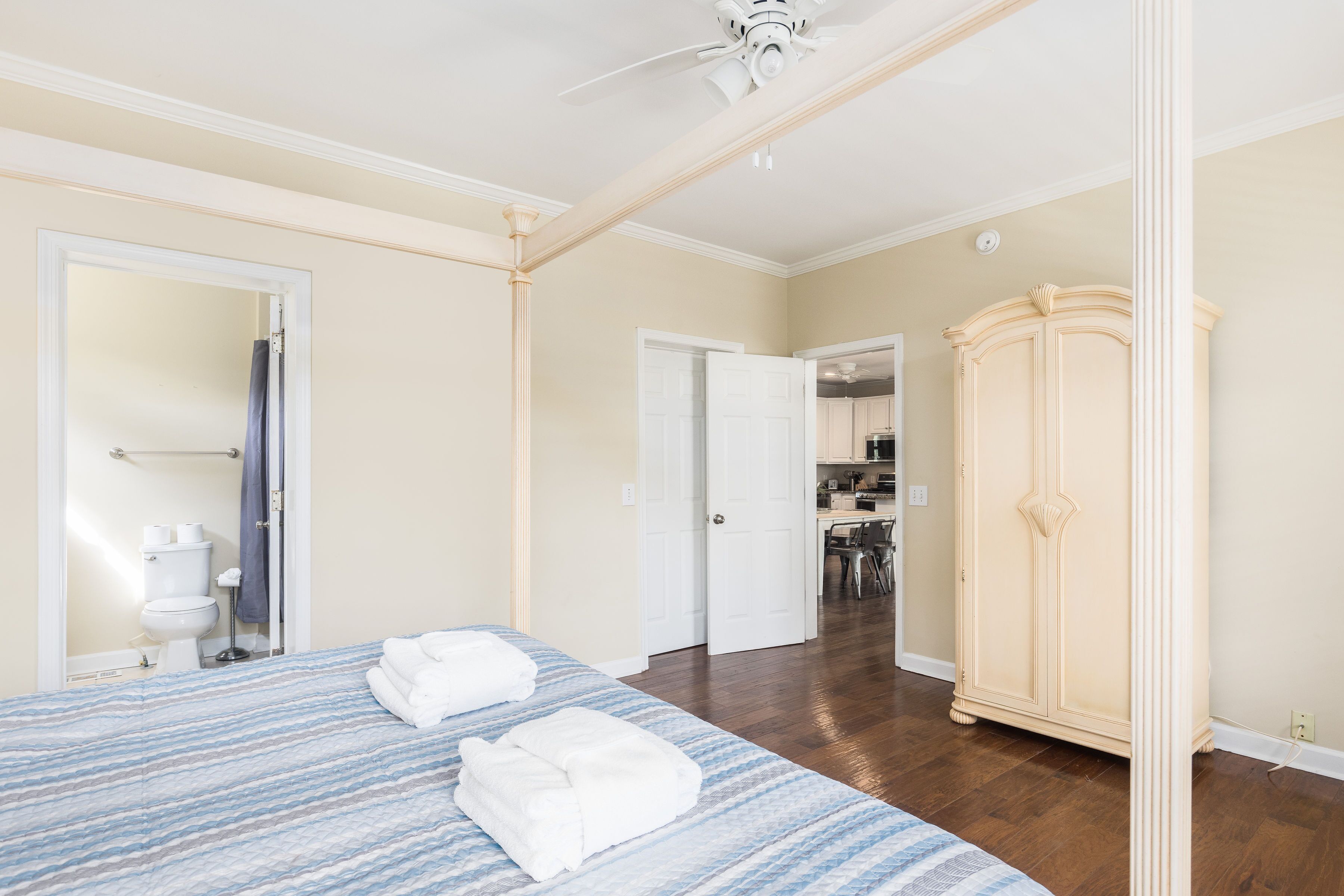 A bedroom with a large bed, a wardrobe, and a bathroom visible through an open door.