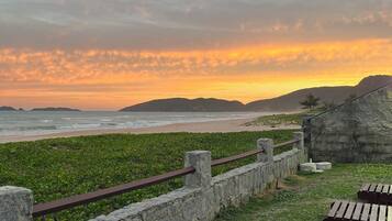 A coastal area with a stone wall and wooden benches overlooking the beach.