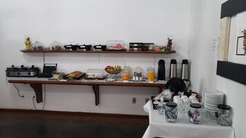 A buffet setup with various food items, a coffee machine, and a fruit bowl.