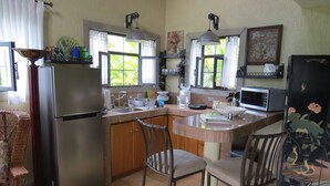 Eine Küche mit Kühlschrank, Mikrowelle, Spüle und Barhocker.