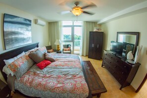 Ein Schlafzimmer mit einem großen Bett, einem Schminktisch, einem Fernseher und einem Deckenventilator.