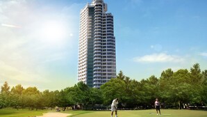 A tall, modern building with a unique curved top, surrounded by a well-maintained golf course with trees and a clear sky.