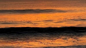 A sunset over the ocean with calm waters reflecting the orange sky. - 1ST STREET II BEACH HOUSE, UPDATED DOG FRIENDLY  FENCED IN YARD 1 BLOCK TO BEACH (St. Augustine)