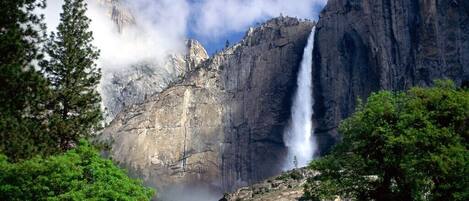 Una cascada en una zona montañosa con abundante follaje verde.