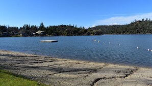 Un lago con un muelle y cisnes, rodeado de árboles y colinas.