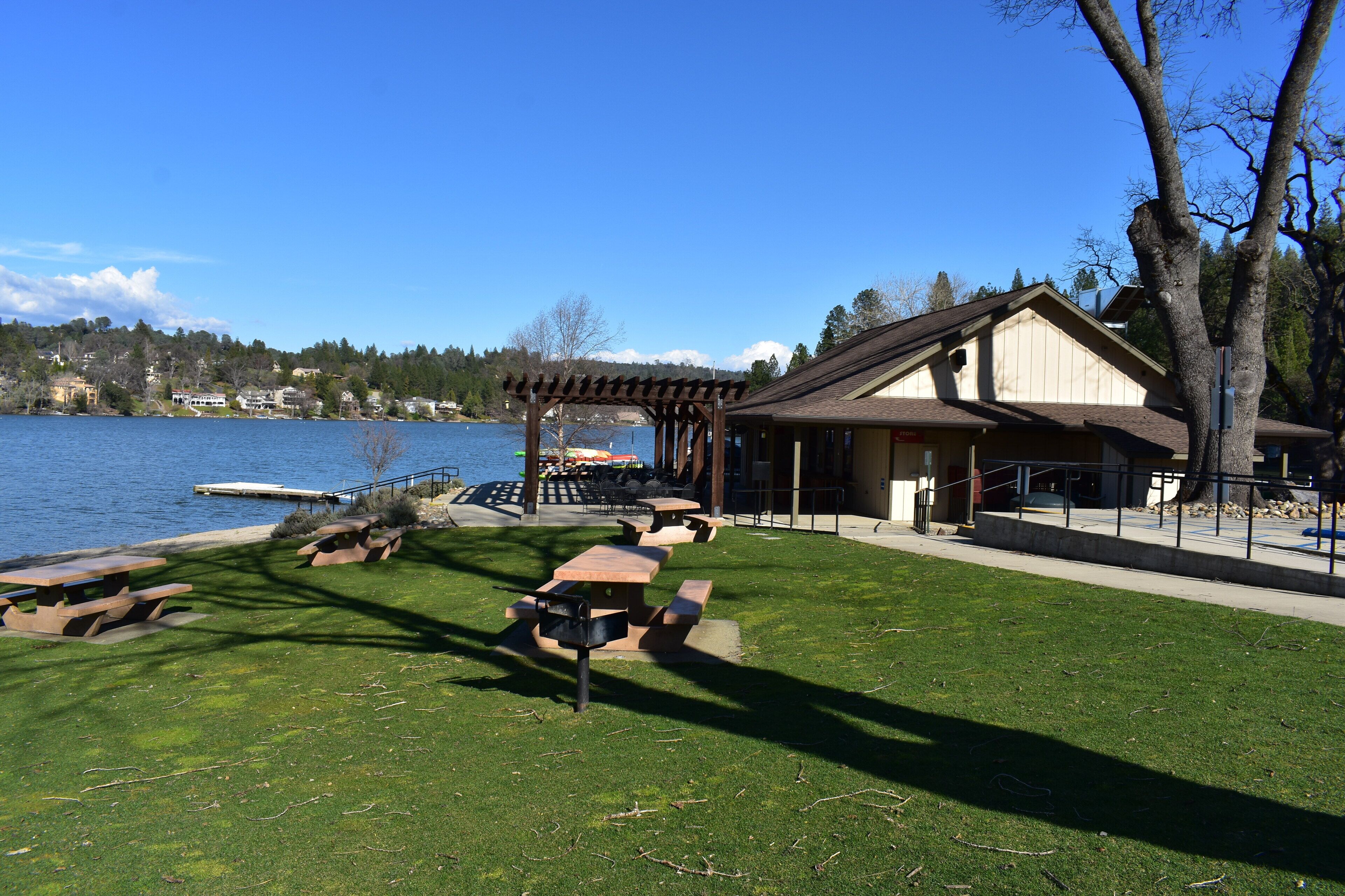 Un parque junto al lago con mesas de picnic y un pabellón.