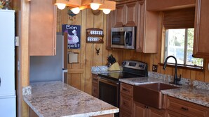Una cocina con armarios de madera, encimeras de granito, electrodomésticos de acero inoxidable y una ventana con vistas.
