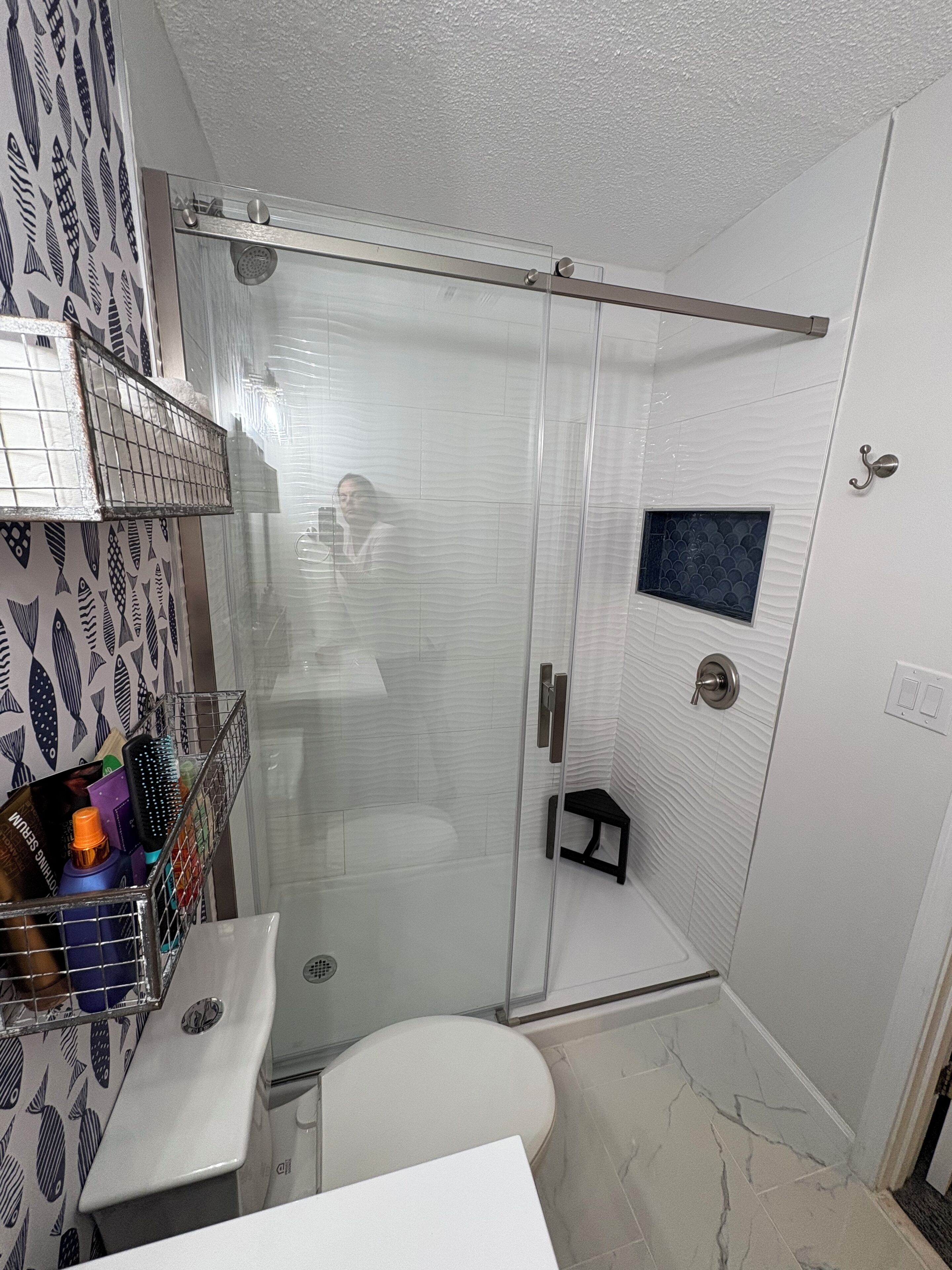 A bathroom with a glass shower enclosure, a white toilet, and a sink with a mirror.