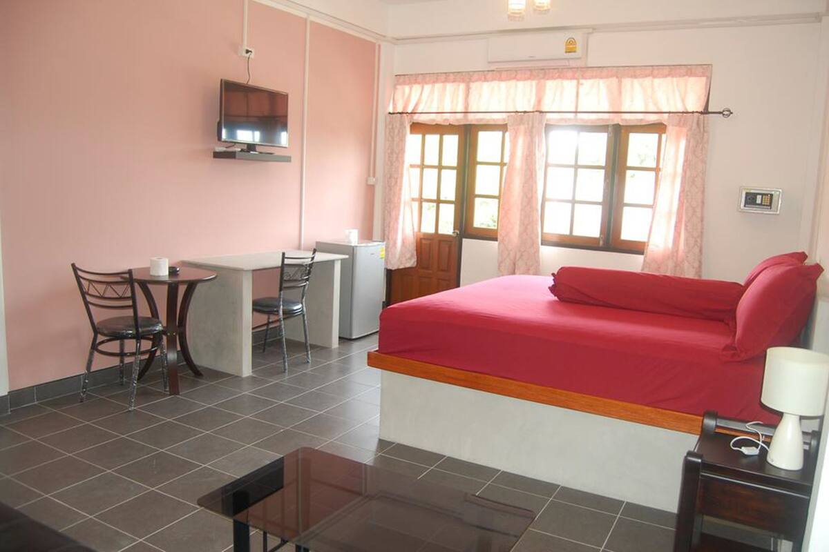 A bedroom with a bed, a desk, a chair, and a TV.