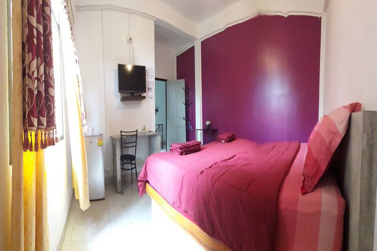 A bedroom with a bed, a desk, a chair, and a television.