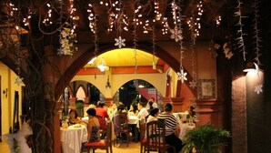 An indoor dining area with tables and chairs, decorated with hanging lights and floral arrangements. - Casa La Granja (Iloilo)