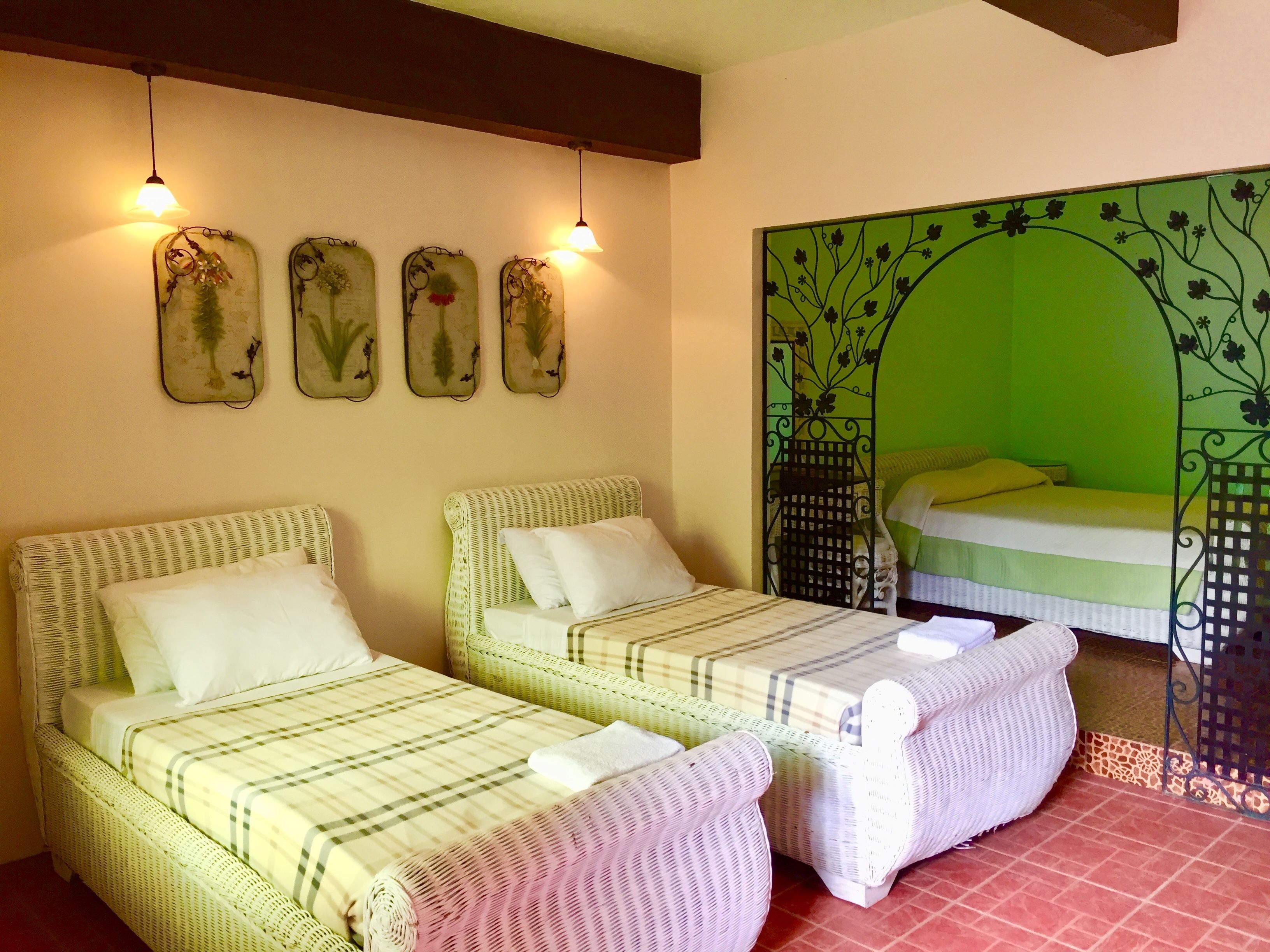 Una habitación con dos camas individuales, una pared verde con diseño floral y una pequeña mesa con una silla.