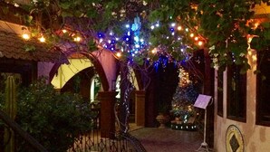 A courtyard with a stone staircase, a pergola with string lights, and a building with a dome and arched entrance. - Casa La Granja (Iloilo)
