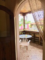 Un patio al aire libre con una mesa redonda y sillas blancas, cerca de madera y suelo de baldosas.