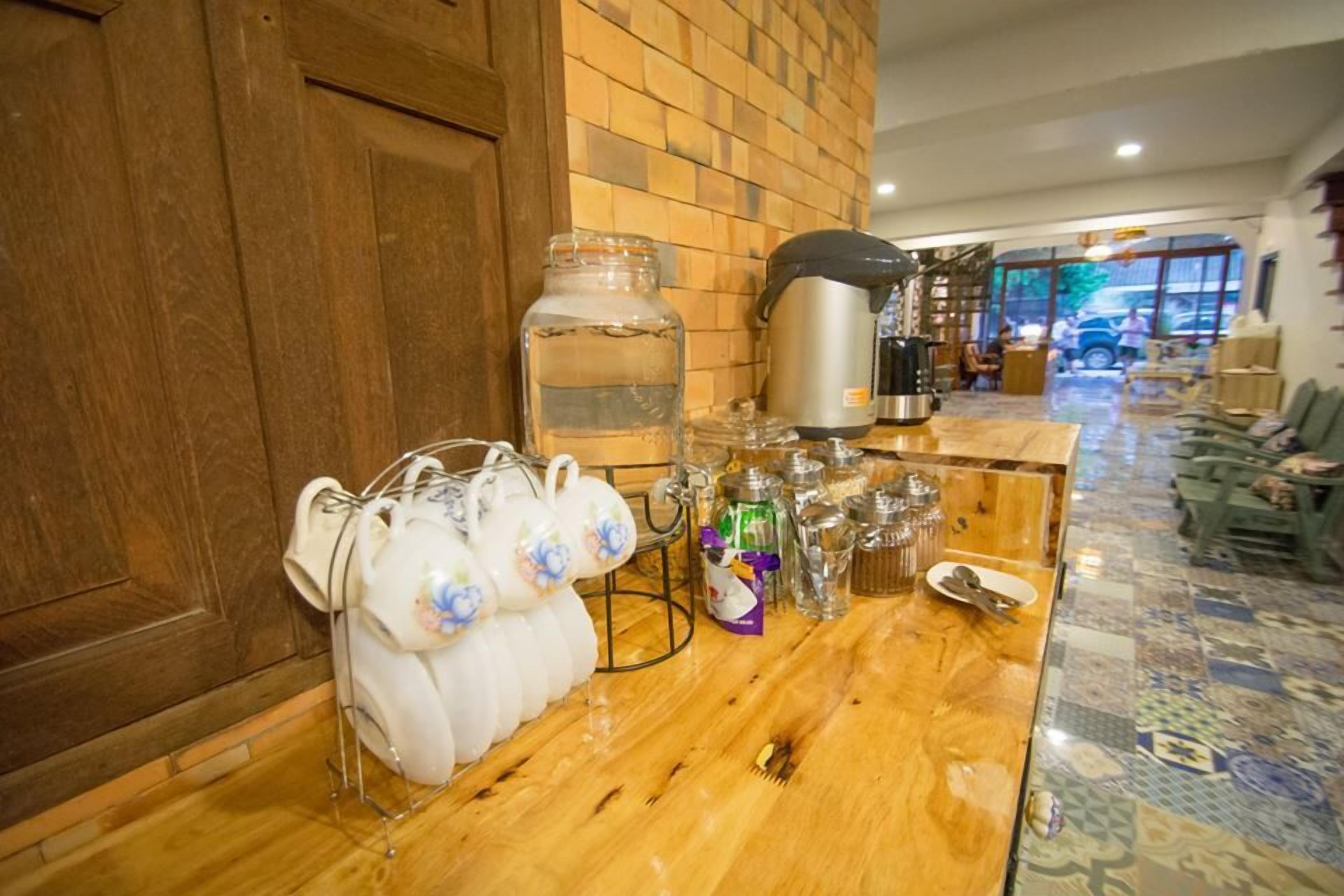 Una zona de bar con mostrador de madera, una máquina de café y un dispensador de agua.
