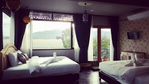 Une chambre d’hôtel avec deux lits, un balcon, une télévision et une vue sur la ville.
