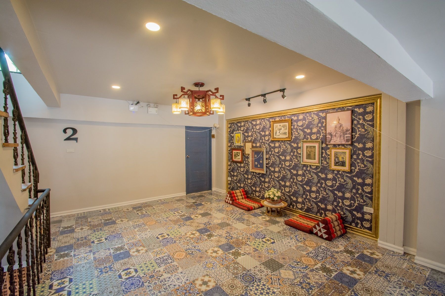 A hallway with a patterned floor, a staircase, and a wall with framed pictures.