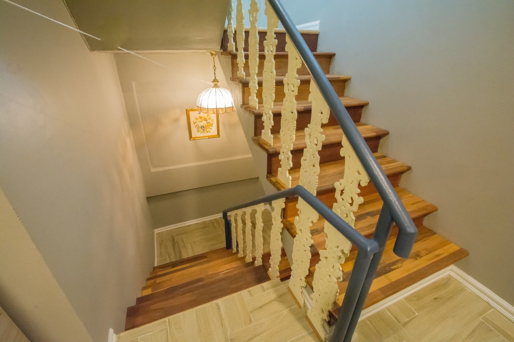 A wooden staircase with a white railing and a light fixture above.