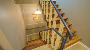A wooden staircase with a white railing and a light fixture above.