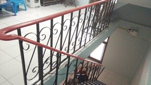 A staircase with a metal railing, a blue handrail, and a tiled floor. - A & P House Charansanitwong (Bangkok)