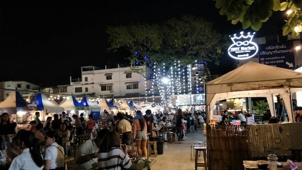 An outdoor market with people dining at tables under string lights. - A & P House Charansanitwong (Bangkok)