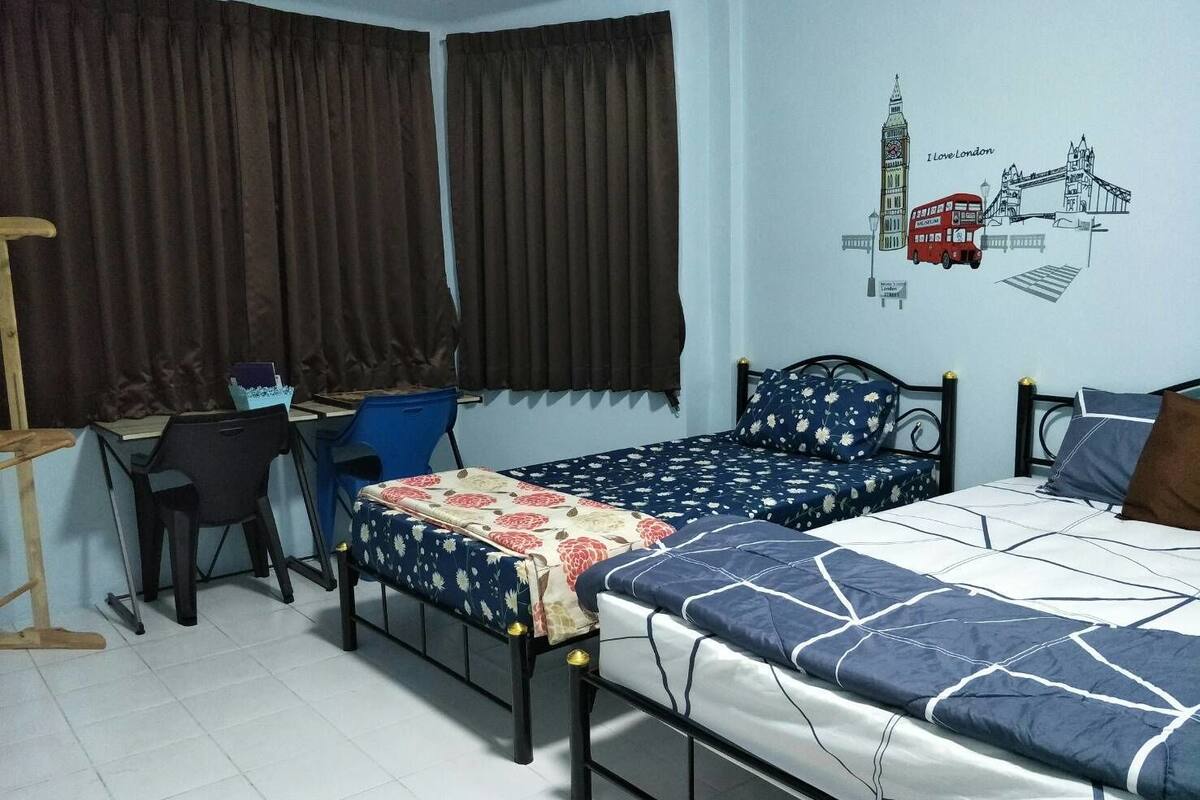 Une chambre avec deux lits simples, un bureau, une chaise et un mur décoré sur le thème de Londres.