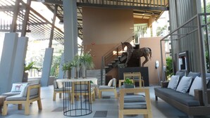 A modern lobby with a staircase, seating areas, and a horse sculpture. - Baan Thew Lom By Woranan (Cha-am)