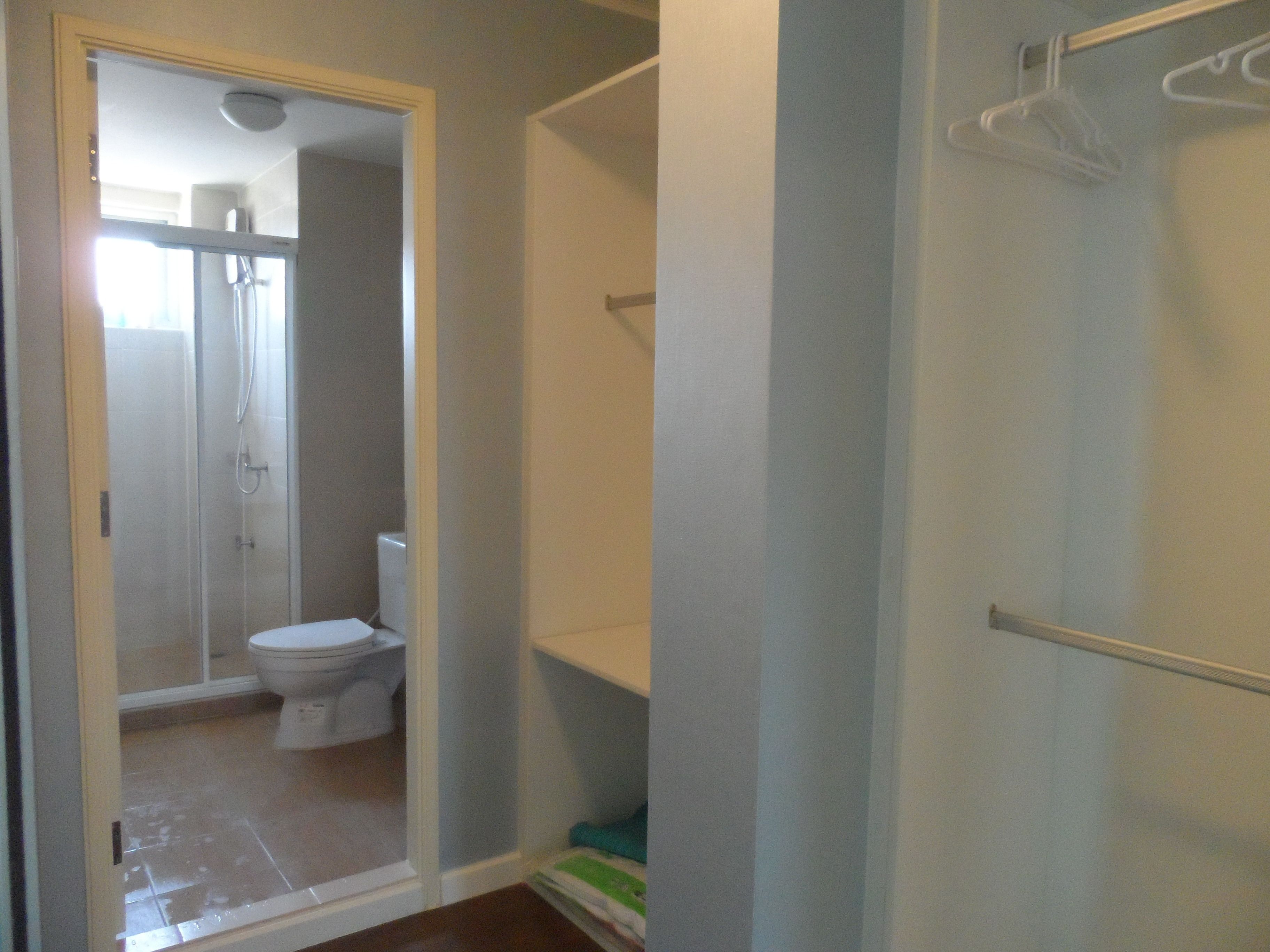 A bathroom with a shower, toilet, and a towel rack.
